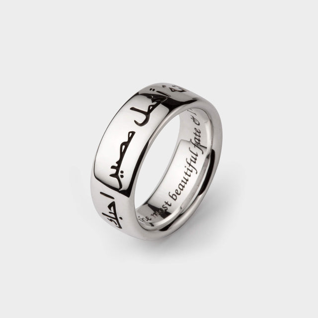 A silver wedding band with Arabic engraving on the outside and the english translation on the inside.